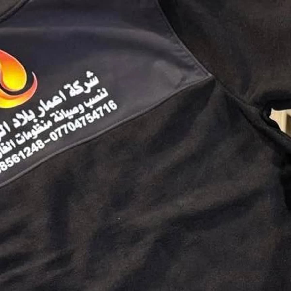 قطعة ملابس سوداء مطبوعة بشعار ومعلومات تواصل من أعمال مطبعة الليث